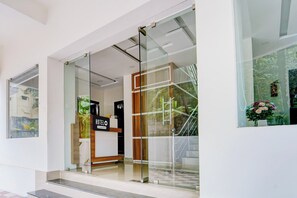 A hotel entrance with a glass door, a reception desk, and a sign that reads 'HOTEL'.