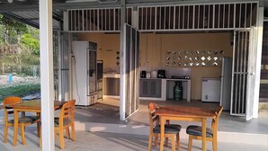 An open-plan living area with a kitchen, dining table, and chairs. - Riverside Holiday Home at Sainam (Khan Rai)