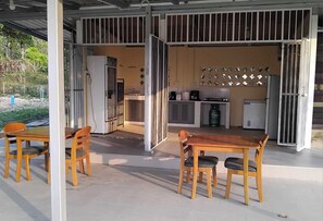 An open-plan living area with a kitchen, dining table, and chairs. - Riverside Holiday Home at Sainam (Khan Rai)