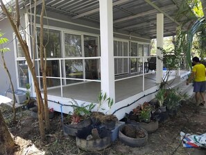 A covered outdoor area with a porch, potted plants, and a person in a yellow shirt.