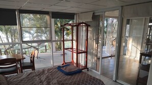 A bedroom with a bed, a desk, and a chair, large windows, and a sliding glass door leading to an outdoor area. - Riverside Holiday Home at Sainam (Khan Rai)