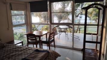 Una habitación con cama, una mesa y sillas, y un ventanal con vistas al exterior.