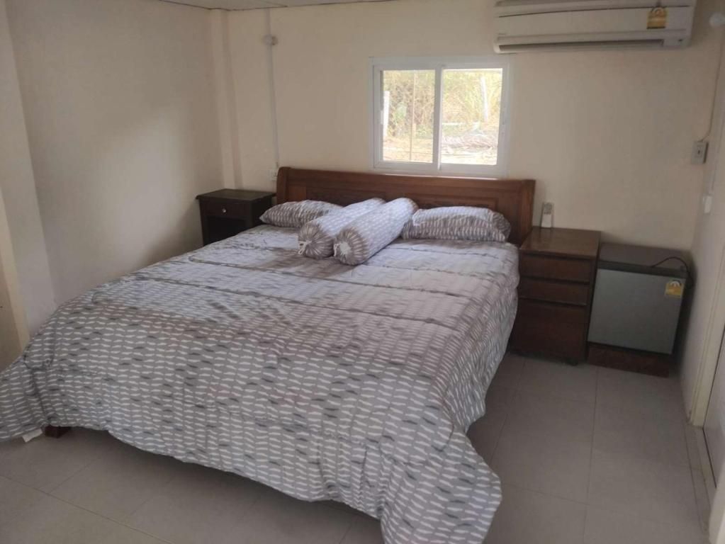 Une chambre à coucher avec un lit, une table de chevet, une commode et une fenêtre.