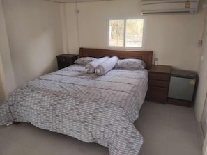 A bedroom with a bed, a nightstand, a dresser, and a window.
