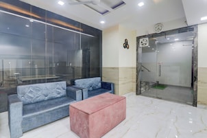 Un vestíbulo moderno con zona de estar, un reloj y un ascensor de vidrio.