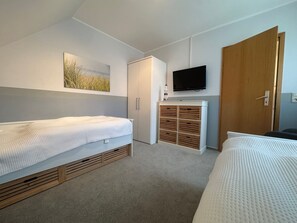 A bedroom with two beds, a television, a wardrobe, and a small cabinet. - Jacobihof - Fiete - Jacobihof "Fiete" 3-room apartment near the beach in a quiet (Dahme)