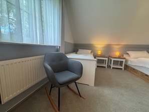 A bedroom with a single bed, a chair, two bedside tables with lamps, and a radiator. - Jacobihof - Fiete - Jacobihof "Fiete" 3-room apartment near the beach in a quiet (Dahme)