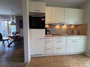 A modern kitchen with white cabinets, a Bosch oven, and a coffee maker. - Jacobihof - Finn - "Finn," a 3-room apartment near the beach in a quiet cul-de-sac (Dahme)
