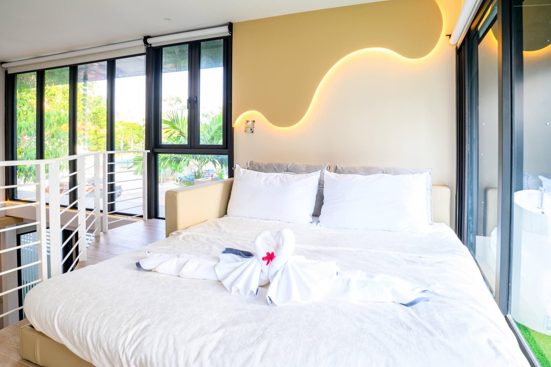 Une chambre d’hôtel avec un grand lit, un balcon et une vue sur la verdure.