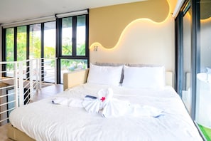Une chambre d’hôtel avec un grand lit, un balcon et une vue sur la verdure.