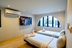 A hotel room with two beds, a flat-screen TV, an air conditioner, and a window with a view of the outside. - Modern Spacious 3 beds Pool Villa BA1 (Pattaya)