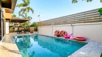 A swimming pool with a tiled edge, surrounded by a fence, and featuring inflatable toys.