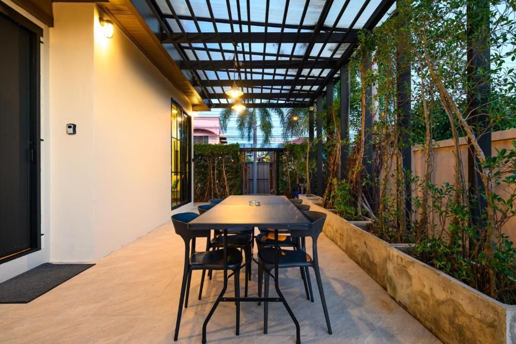 Un espace extérieur aménagé pour les repas, avec une table et des chaises, entouré de plantes et agrémenté d’une pergola.