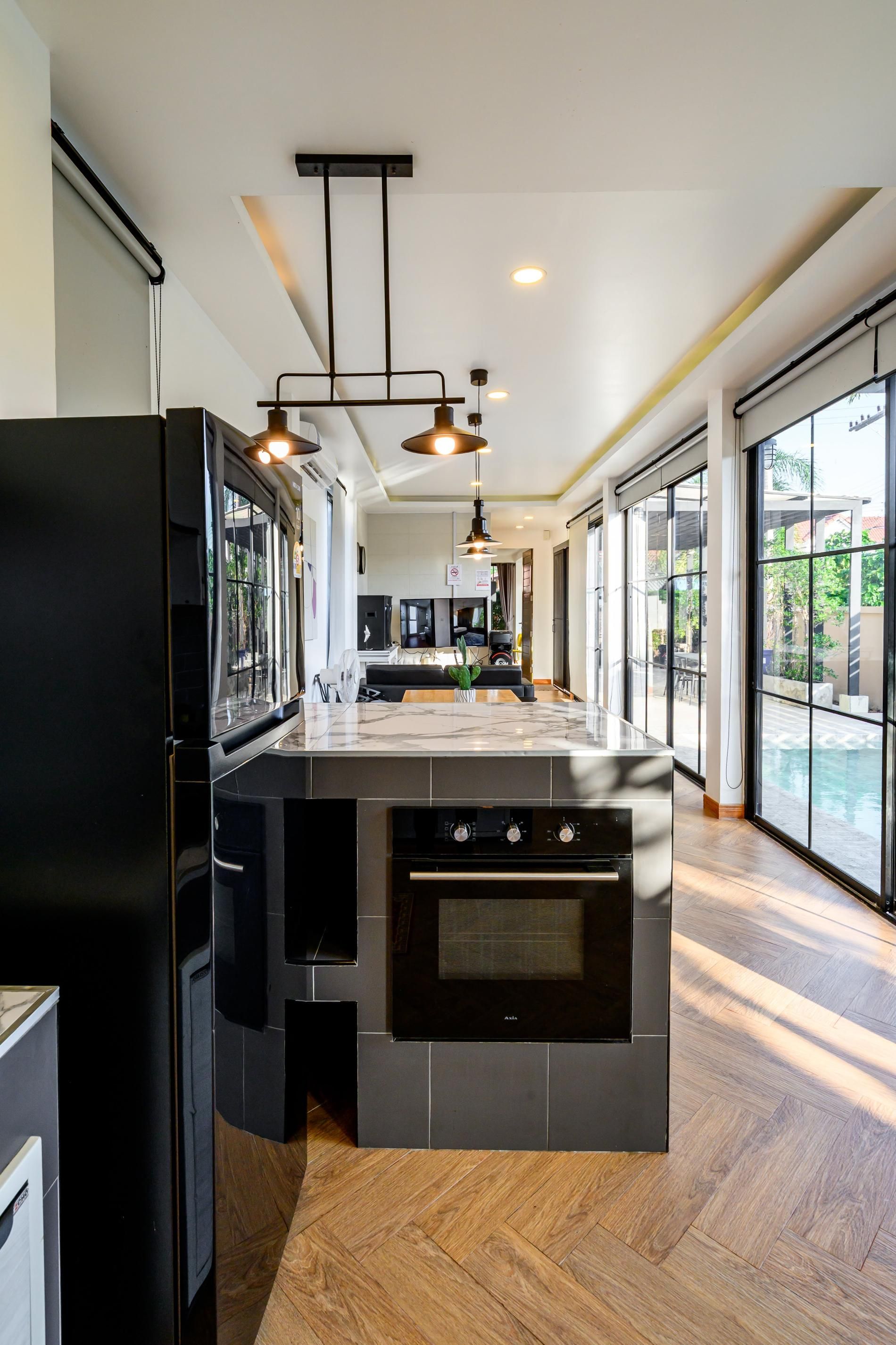 A modern kitchen with a large island, built-in appliances, and a view of a swimming pool.