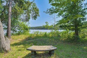 A stone bench surrounded by trees and a lake. - Gilmore Lake Family Escape w/ Game Room & Dock! (Minong)