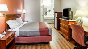 Ein Hotelzimmer mit Bett, Nachttischen, einem Schreibtisch mit Stuhl, einem Fernseher und einem Spiegel.