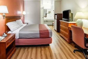 Een hotelkamer met een bed, nachtkastjes, een bureau met stoel, een televisie en een spiegel.