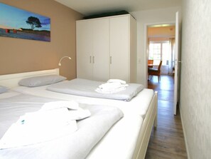 A hotel room with two beds, a wardrobe, and a painting on the wall. - Kiek Ut 9, Holiday Apartment 2 (Wyk auf Foehr)