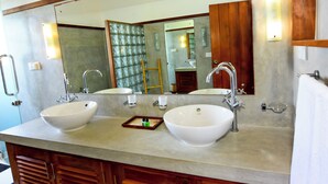 Un baño con dos lavamanos, un espejo grande y armarios de madera.