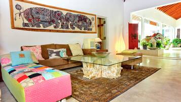 A living room with a sofa, a glass coffee table, and a large abstract painting on the wall.