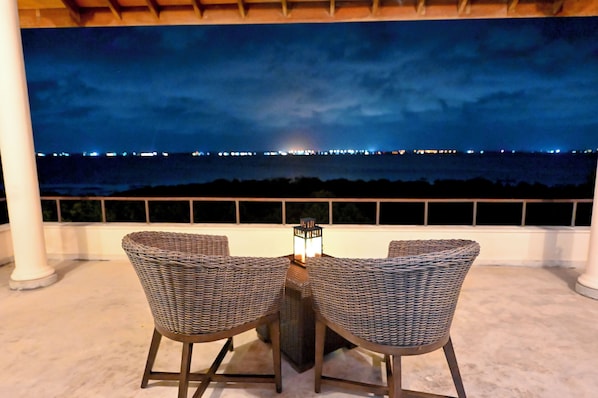 An outdoor seating area with two wicker chairs and a table, overlooking a cityscape at night. - Hotel with 4 bedrooms and AC in peaceful Negombo (Negombo)