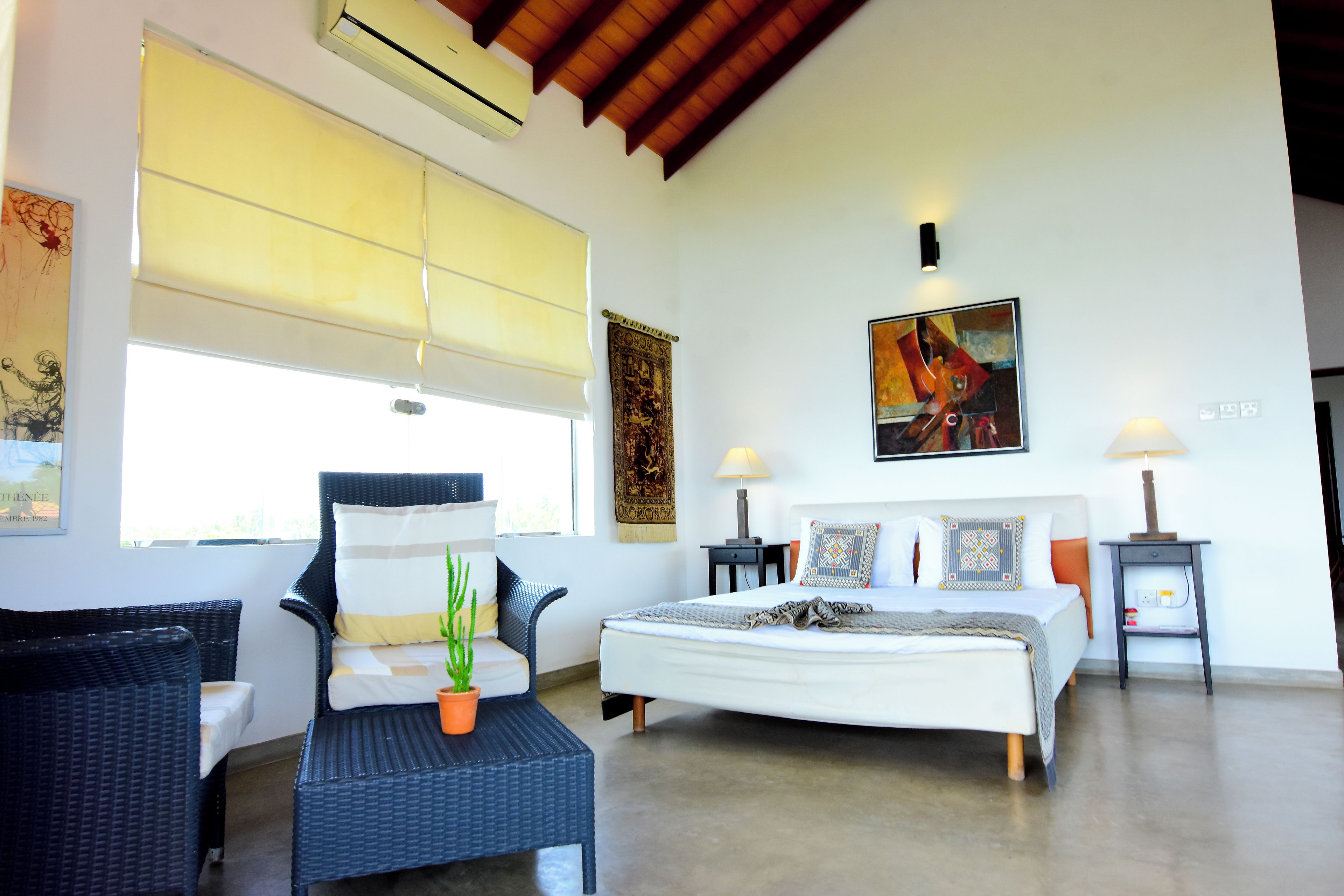 A bedroom with a bed, a nightstand, a chair, a window with blinds, and a painting on the wall.