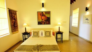 Habitación de hotel con una cama grande, dos mesitas de noche, un cuadro colgado en la pared y un tapiz.