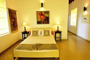 A hotel room with a large bed, two bedside tables, a wall-mounted painting, and a tapestry. - Hotel with 4 bedrooms and AC in peaceful Negombo (Negombo)