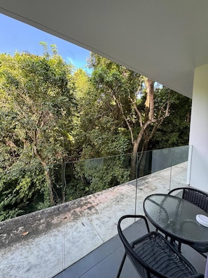 A balcony with a glass railing, a table, and two chairs. - Utopia D Private & Quiet · 1BR · Pets OK · 500Mbps (Tambon Rawai)