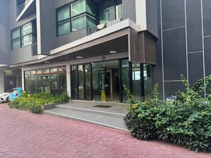Un edificio moderno con ingresso in vetro, gradini che conducono ad esso e un'auto blu parcheggiata di fronte.
