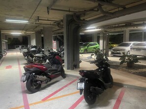 A parking garage with motorcycles and cars parked. - Top-Floor Sea-View Studio, Nai Harn, Rooftop Pool (Tambon Rawai)