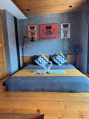 A modern bedroom with a bed, pillows, a fan, and wall art. - Quiet Sea-View Studio, Walk to Nai Harn Beach (Tambon Rawai)