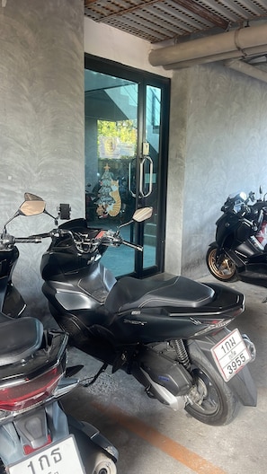 A motorcycle parked indoors with a visible license plate and a glass door in the background. - Quiet Sea-View Studio, Walk to Nai Harn Beach (Tambon Rawai)