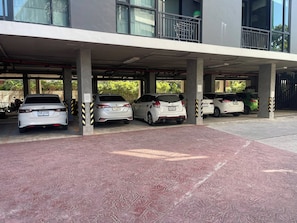 A covered parking area with multiple cars parked under a building. - Sunrise Studio, Nai Harn, Desk, Rooftop Pool (Tambon Rawai)