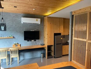 A modern kitchen with a built-in stove, a refrigerator, and a flat-screen TV mounted on the wall. - Nai Harn Studio, Steps to Everything, Pool, Gym (Tambon Rawai)