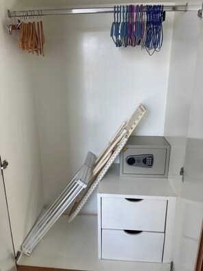 A storage closet with a metal rod rack holding hangers, a white storage cabinet with a keypad lock, and a white drawer unit. - Quiet & Cozy 1BR, Pool, Rawai, Walk to Gyms (Rawai)