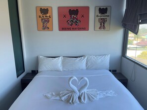 A hotel room with a bed, pillows, and three wall art pieces. - Quiet Sunrise Studio, Nai Harn, Pool and Gym (Tambon Rawai)