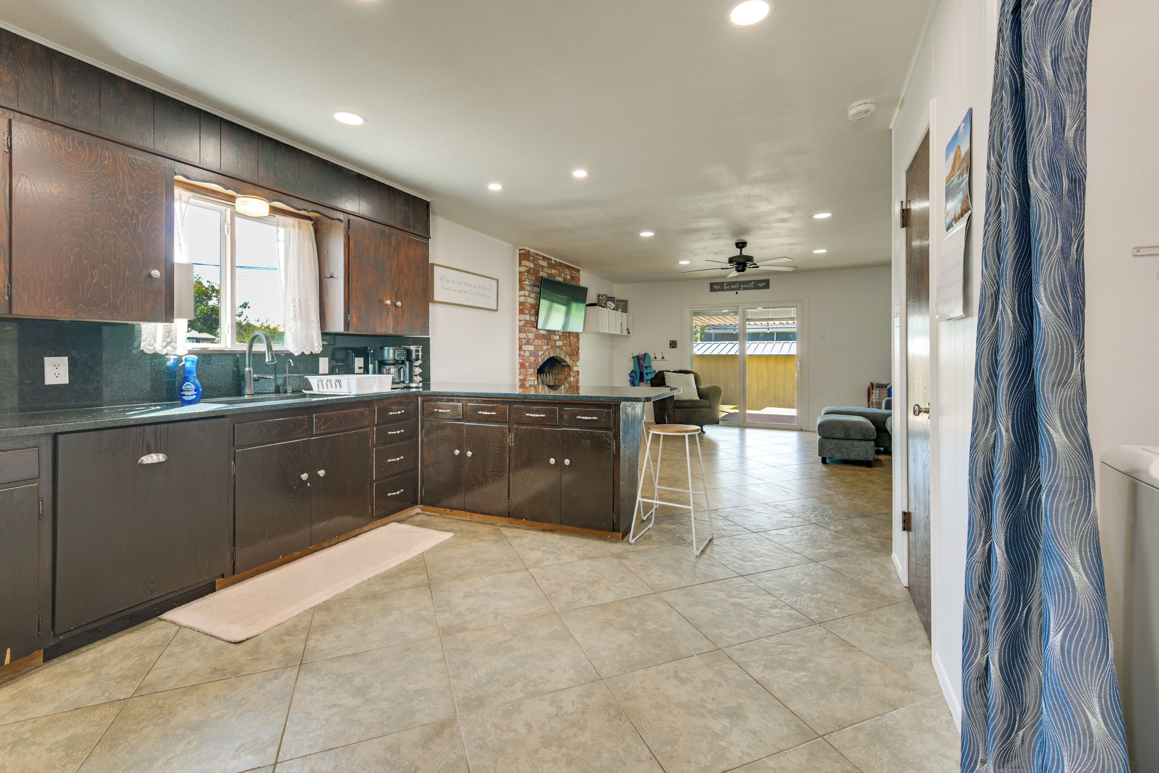 A modern kitchen with dark wood cabinets, a large island, and a view into the dining area.