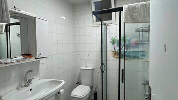 A bathroom with a white sink, toilet, and shower enclosure.