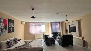 A spacious living room with a large bed, a sofa, a coffee table, and a TV.