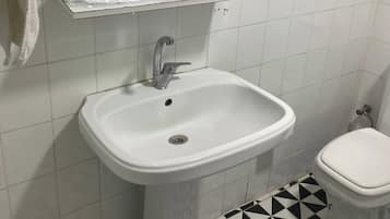 A bathroom with a white sink, a mirror, and a toilet.