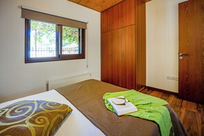 A single bed with a patterned pillow, a green blanket, and an open book on the bed. - Troodos View Garden House - Trimiklini (Trimiklini)