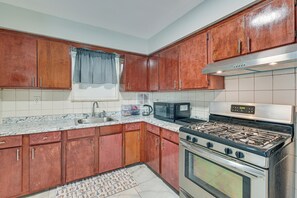 A kitchen with wooden cabinets, a stainless steel stove, a microwave, and a sink.