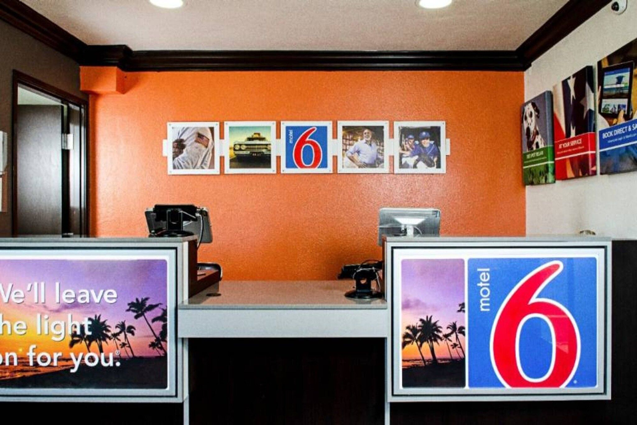 Mostrador de recepción de motel con un letrero con el número '6', una computadora y un teléfono.