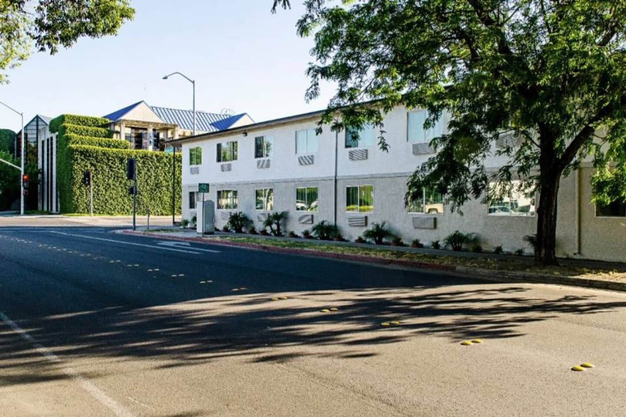 A multi-story building with a flat roof, a gated entrance, and a well-maintained lawn.