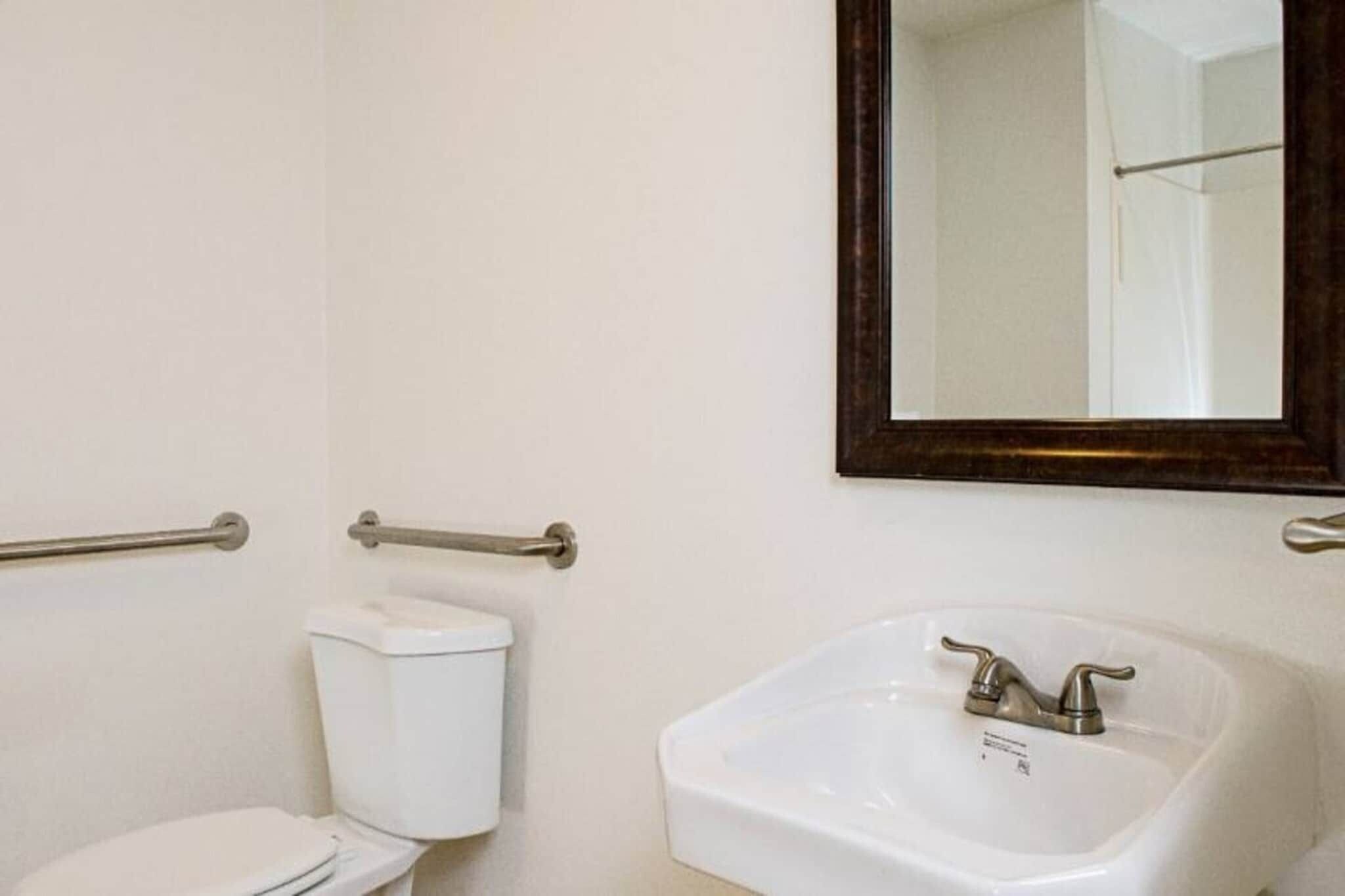 A bathroom with a toilet, a sink, and a mirror.