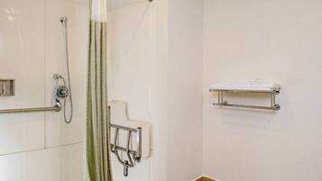 A bathroom with a shower, grab bars, and a towel rack.