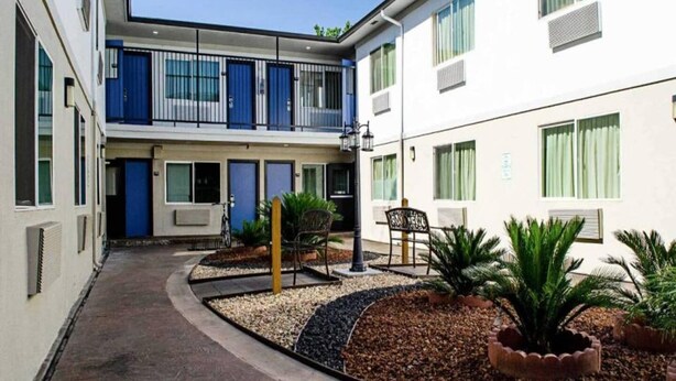 Un edificio de varios pisos con patio interior, mobiliario exterior y plantas en macetas.