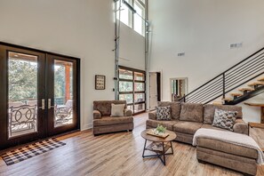 A spacious living room with a large sofa set, a coffee table, and a staircase leading to an upper level. - 'River Bank' Spacious Waterfront Group Getaway (Nashville)