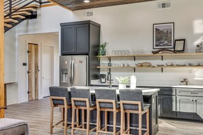 A modern kitchen with a central island, bar stools, and a dining table. - 'River Bank' Spacious Waterfront Group Getaway (Nashville)